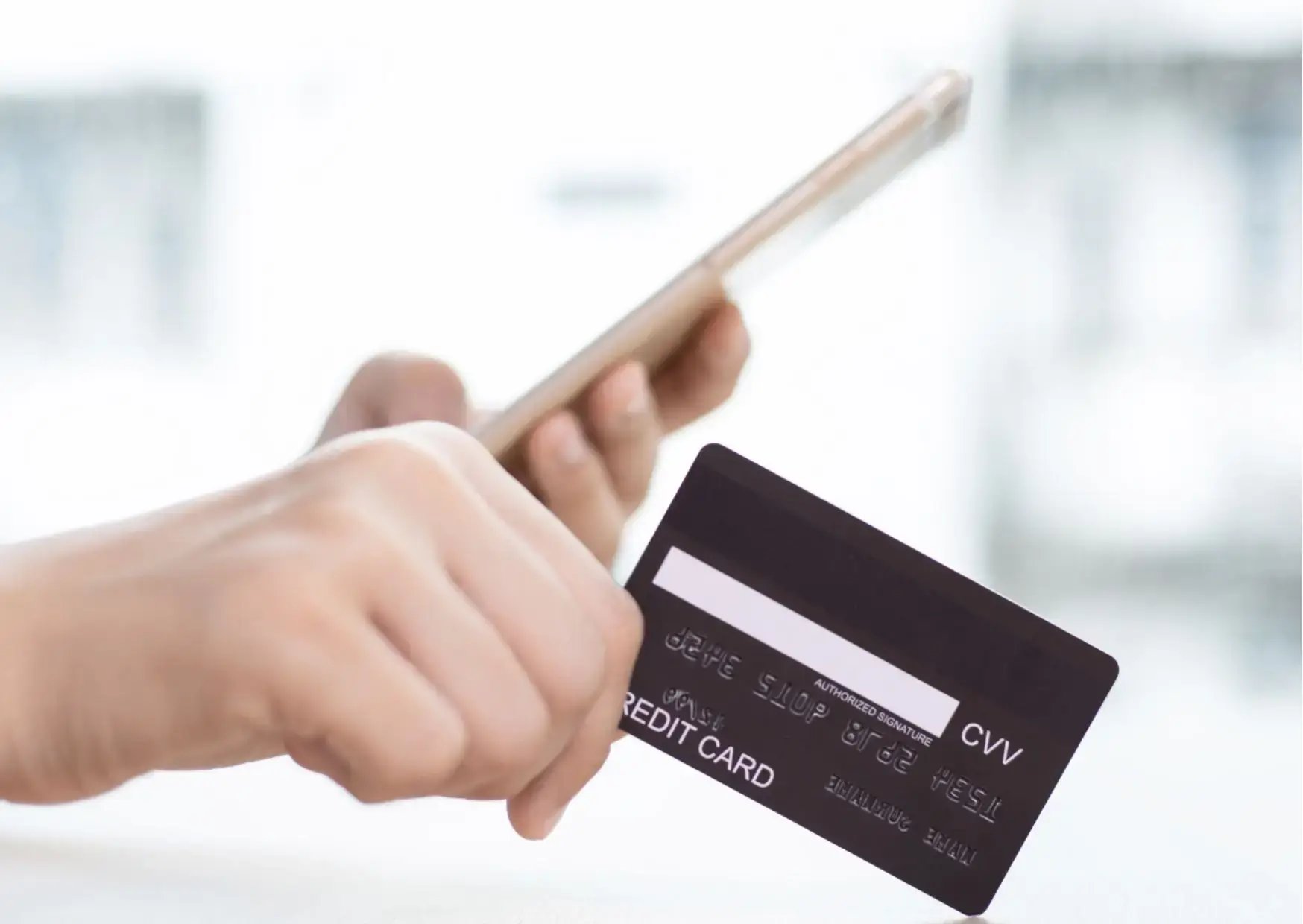close up photo of hands holding credit card and mobile phone